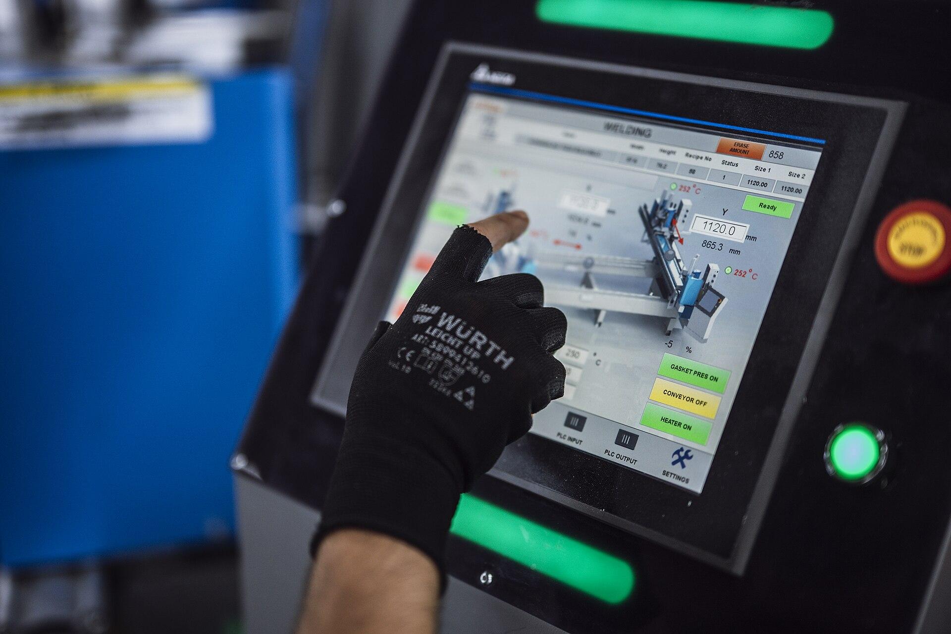 Gloved operator using a touchscreen control panel on a production machine